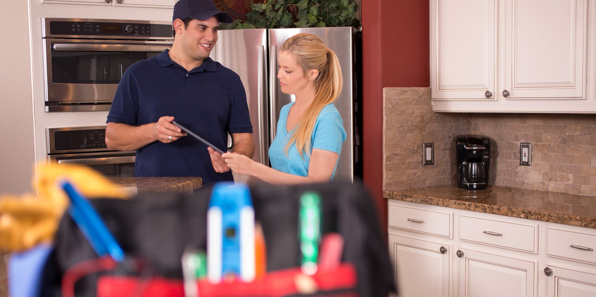 A man and woman in the kitchen talking.