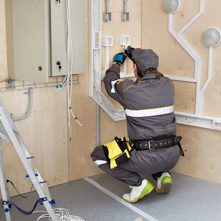 A man in grey work suit fixing electrical wiring.